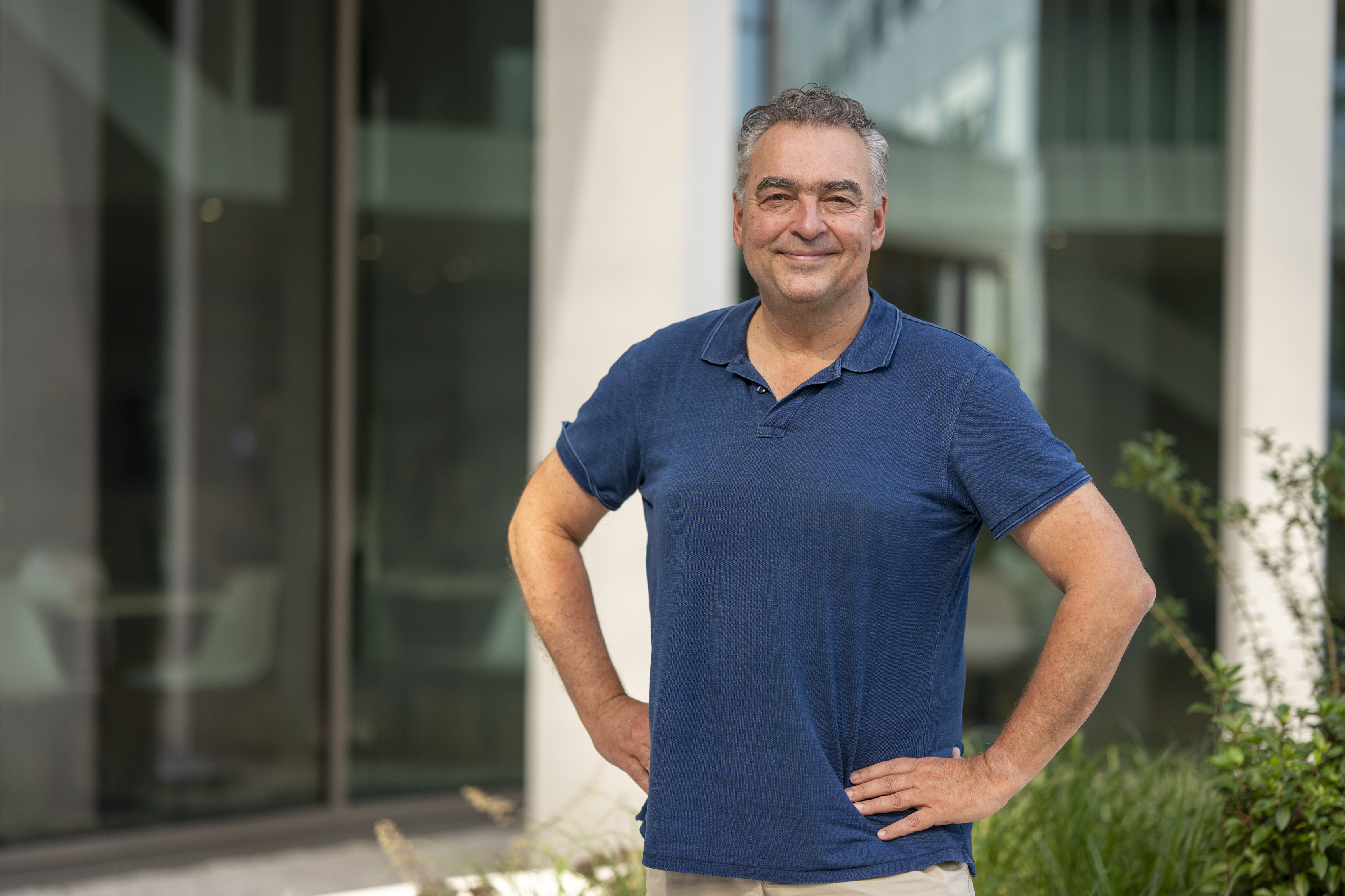 Man met grijs haar en donkerblauw shirt poseert voor camera