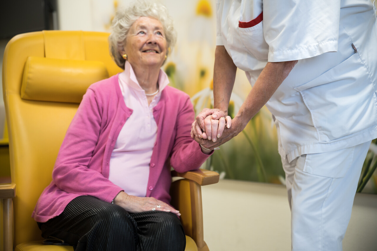 Foto van oudere vrouw in stoel met verpleegkundige
