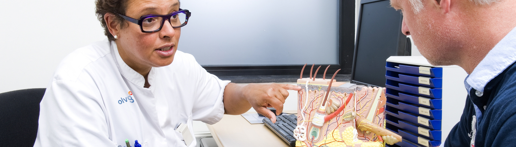 Foto van een zorgverlener die een patiënt uitleg geeft