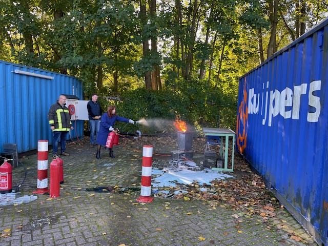 Een vrijwilliger oefent een brand te blussen met een brandblusapparaat 