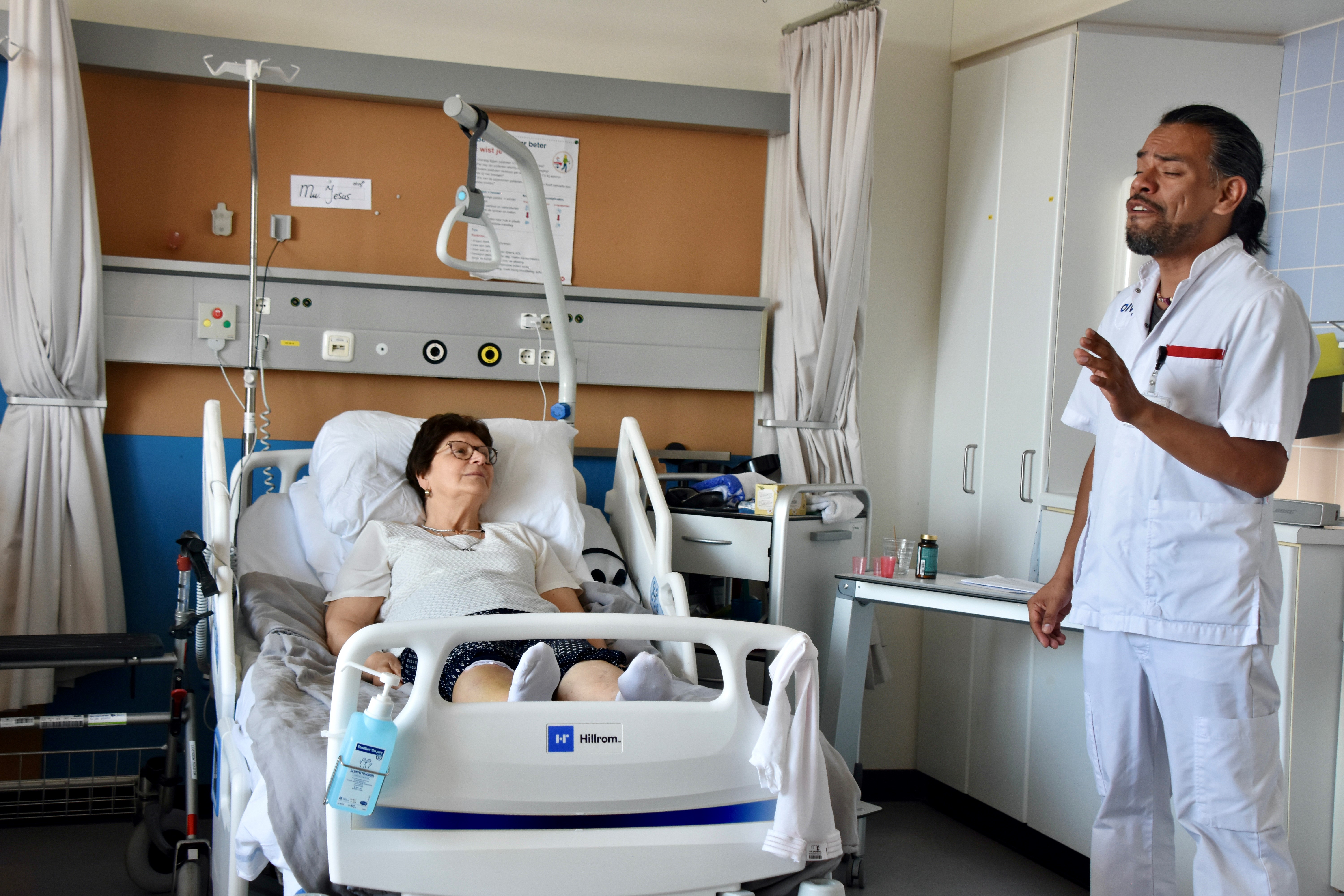 Foto van Luis Carrion die zingt bij het bed van een patiënt