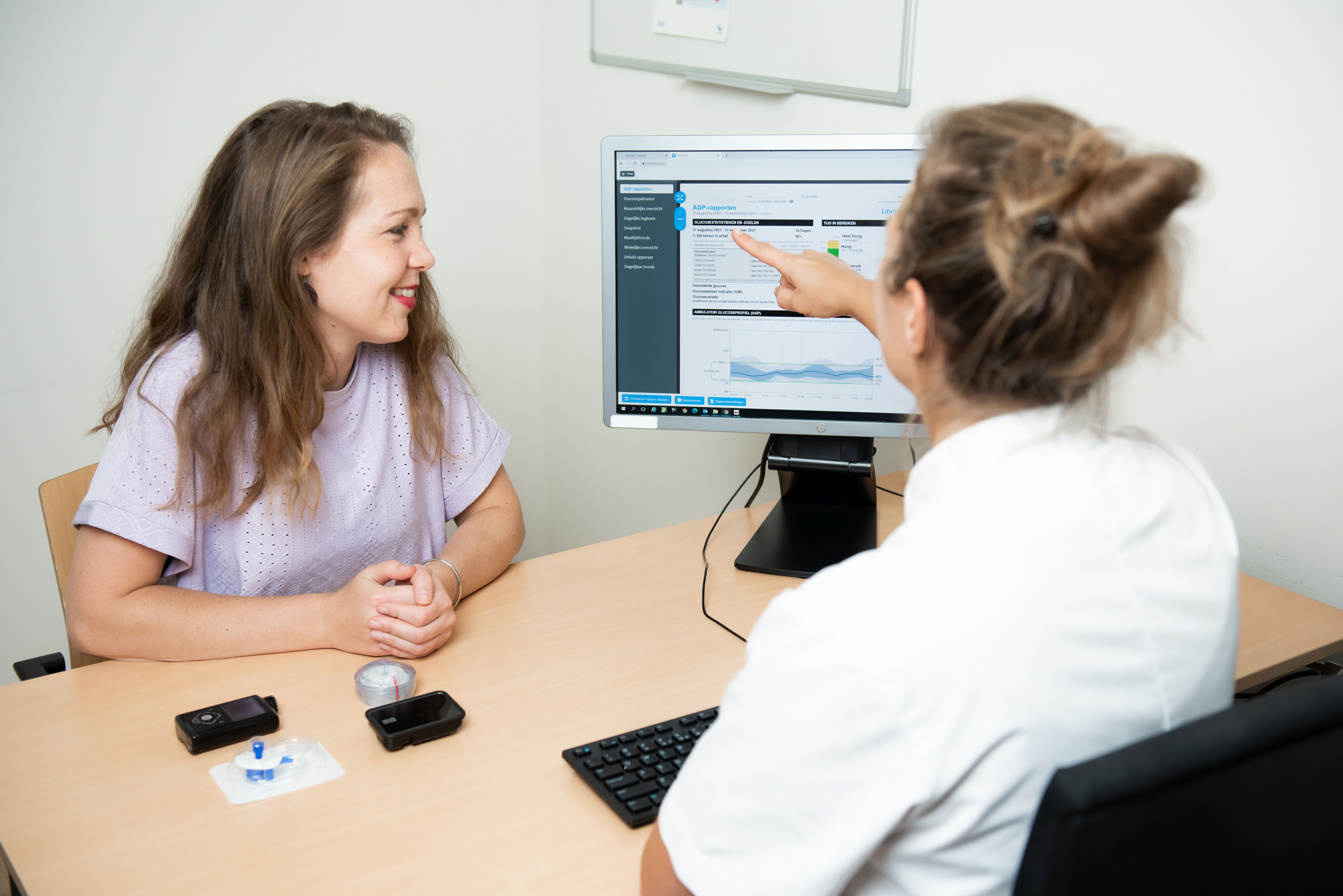 Foto van een zorgverlener die uitleg geeft aan een patiënt