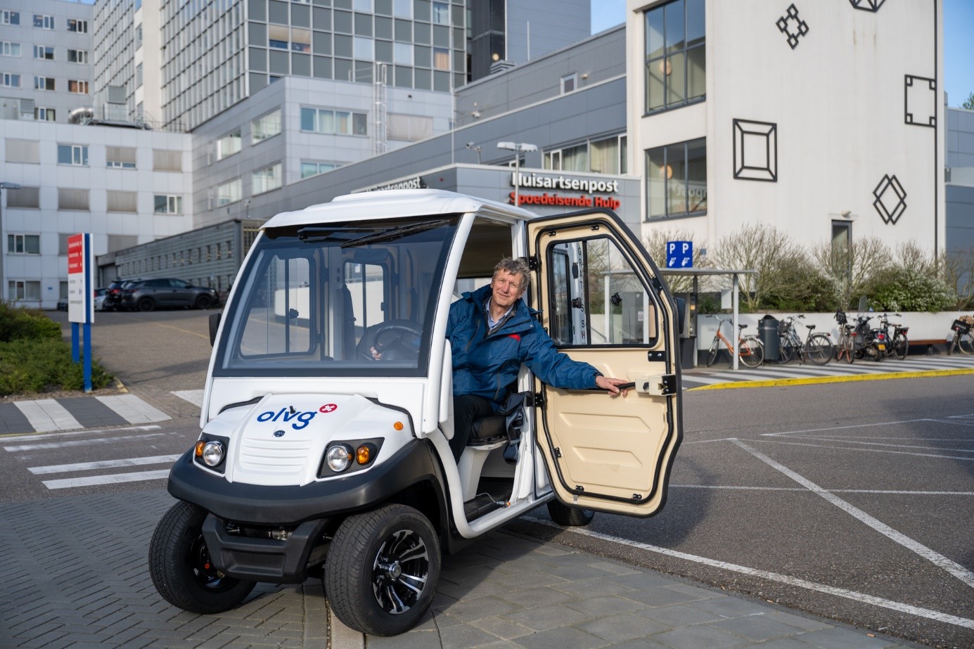 Vrijwilliger rijdt patiënten en bezoekers van het parkeerterrein naar de ingang rijden en andersom