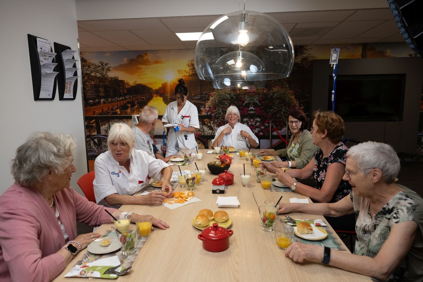 Vrijwilligers zitten samen met patiënten aan een lunchtafel te eten