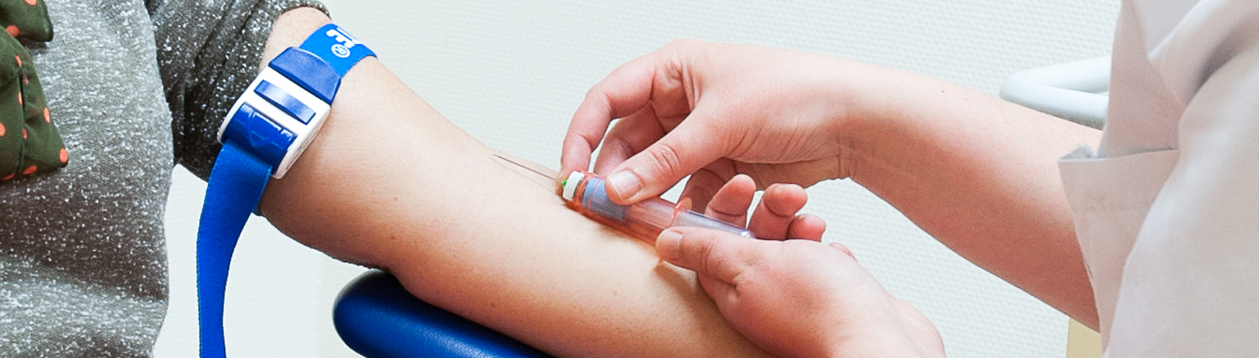 Foto van een zorgverlener die bloed afneemt bij een patiënt