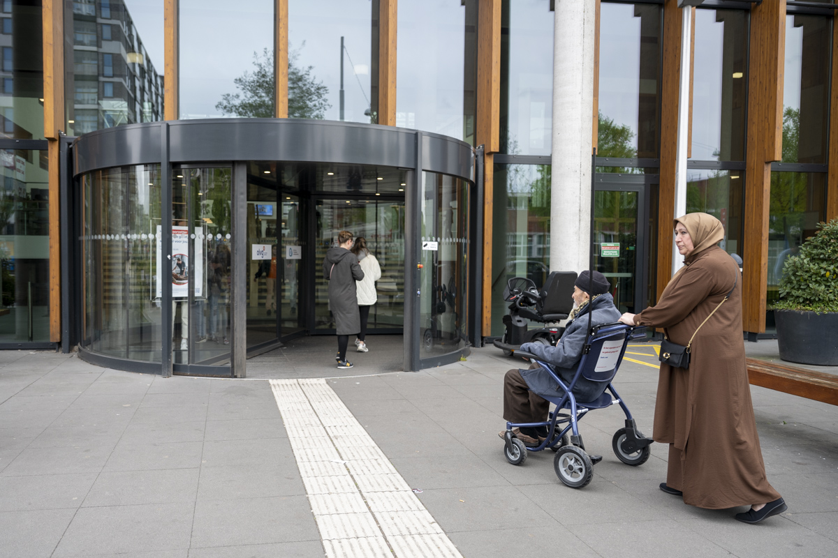 Patiënt in rolstoel en naaste voor entree OLVG West
